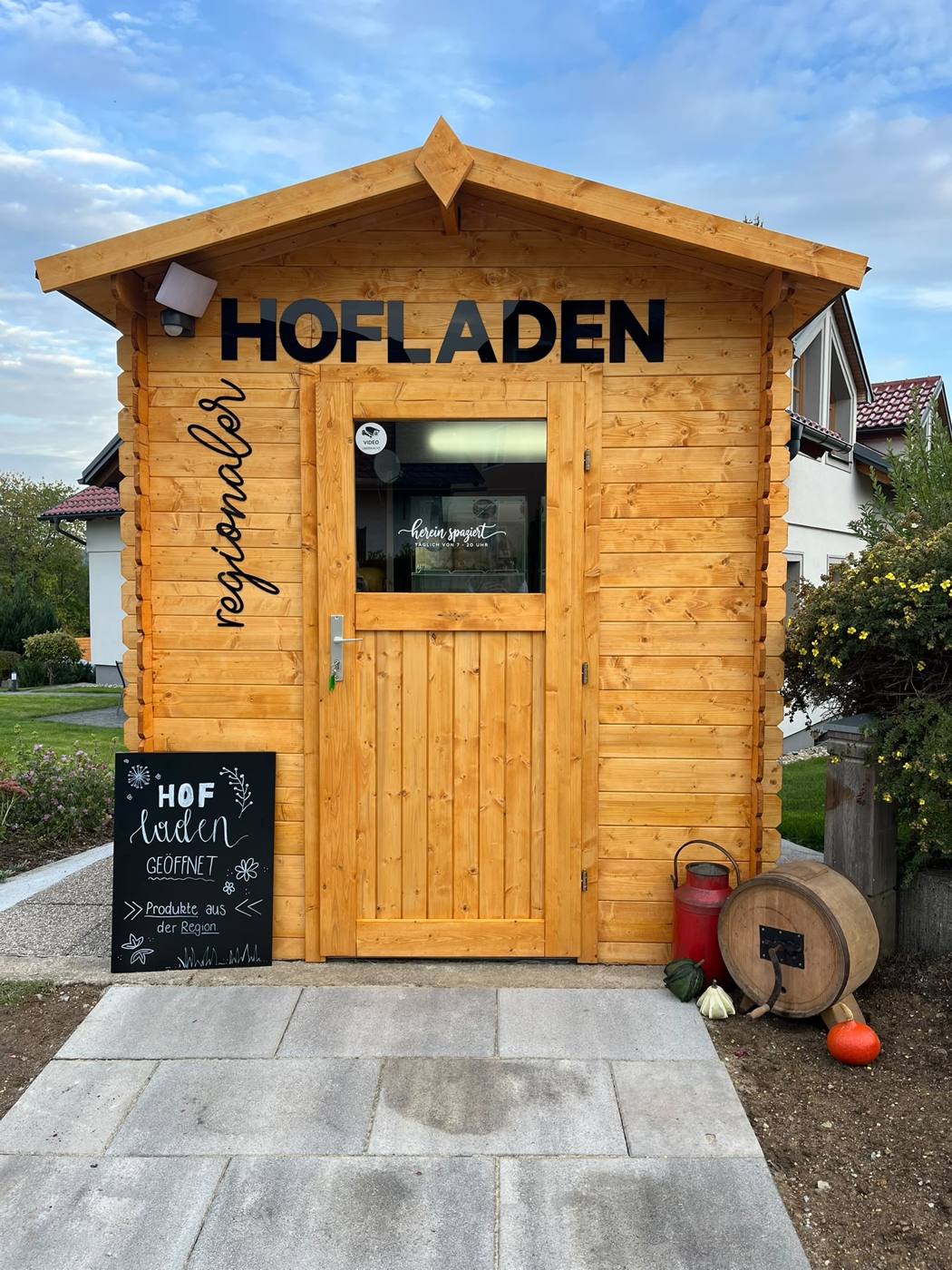 Die Holzhütte des Hofladens mit Kreidetafel „geöffnet“